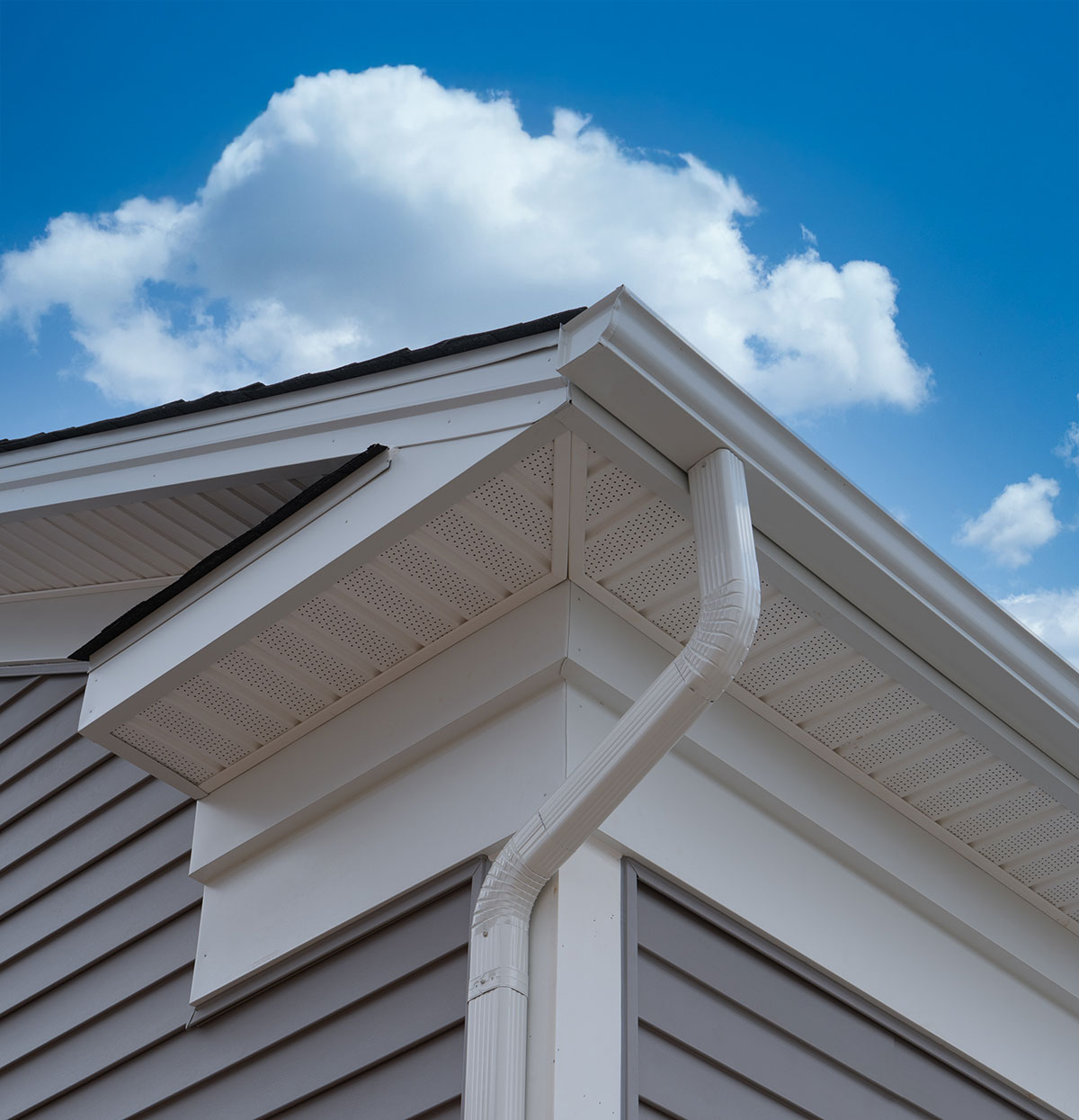 White soffit, fascia and downspout on a home against a blue sky